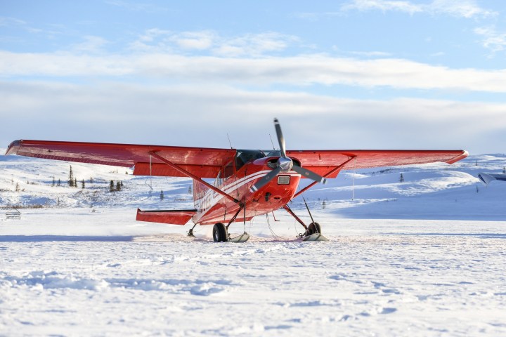 Bushplane on skis, backcountry support on snow-covered runway, clear sky background.