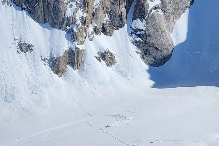 Snow-covered mountain with cliffs and traces of activity on the snow below.