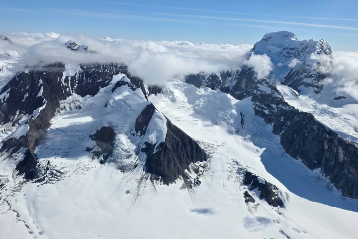 Snow-covered mountain range with scattered clouds and blue sky.