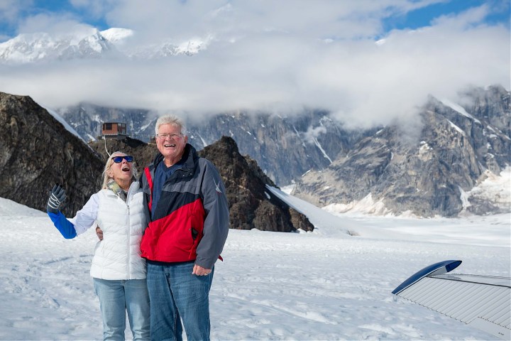 Smiling couple in snow with Denali and Sheldon Chalet on the background