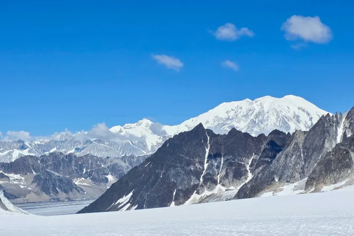 Snow-covered mountains with clear blue sky and sparse clouds on the Pika at Denali National Park with Mt Foraker on the background