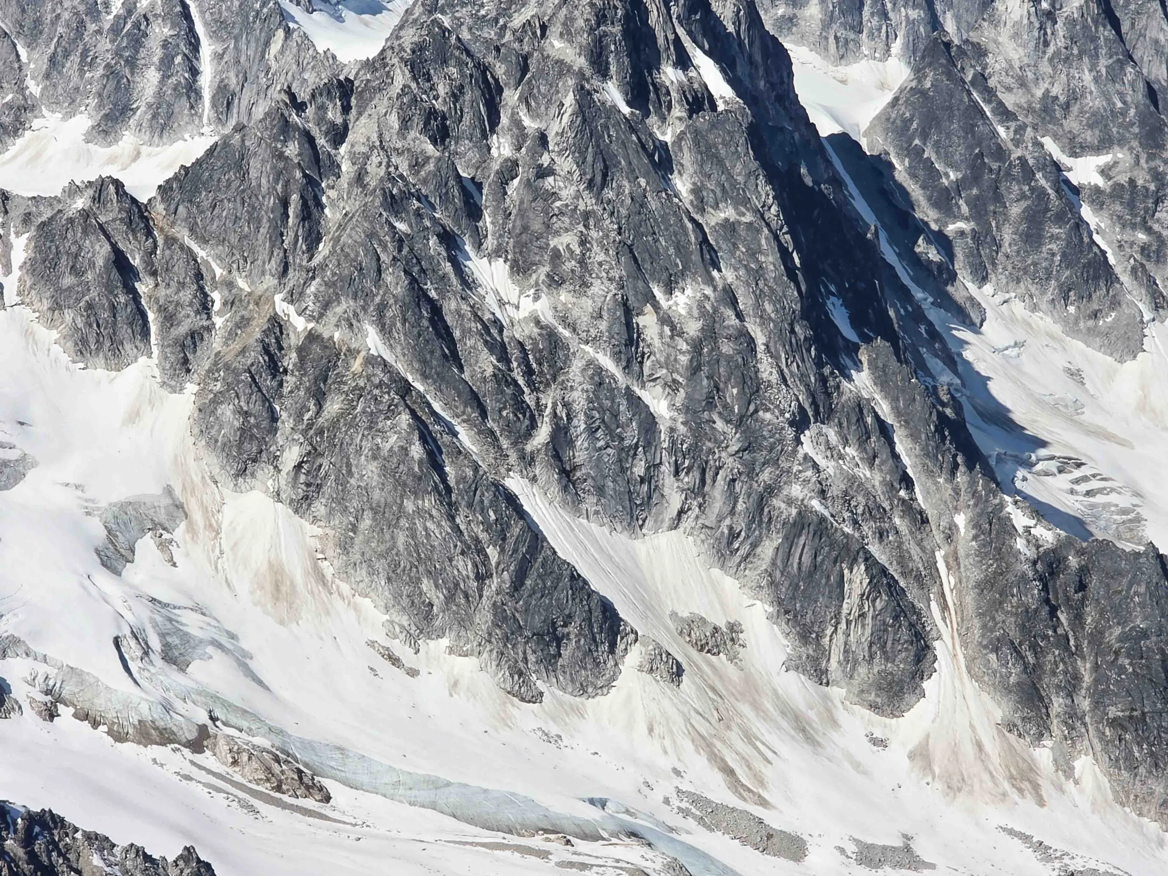 Aerial view of rugged snow-capped mountains under a clear blue sky.