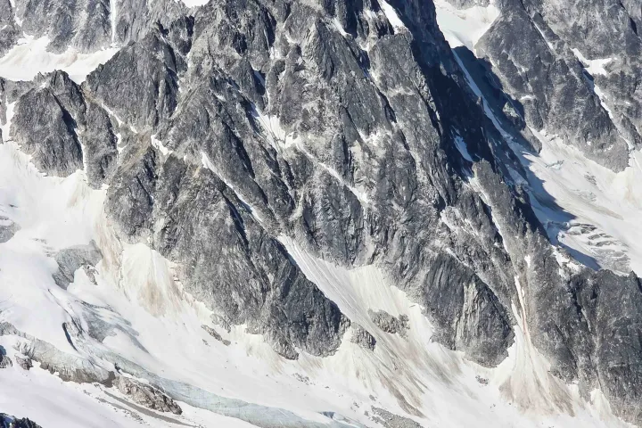 Aerial view of rugged snow-capped mountains under a clear blue sky.
