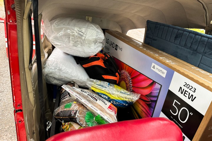 Packed car interior with a TV box, pillows, and assorted items.