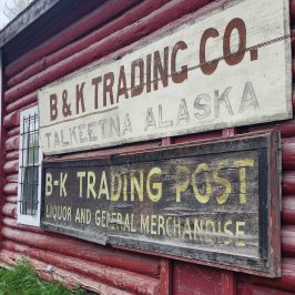 Red wooden building with signs for B&K Trading Co. in Talkeetna, Alaska.