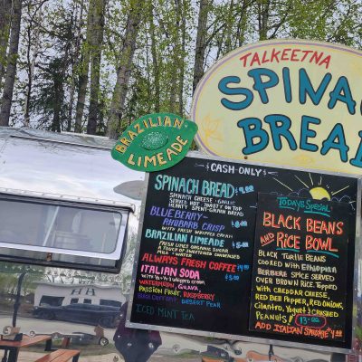 The famous Spinach Bread - Airstream food truck with signs for spinach bread, Brazilian limeade, and black beans and rice bowl.
