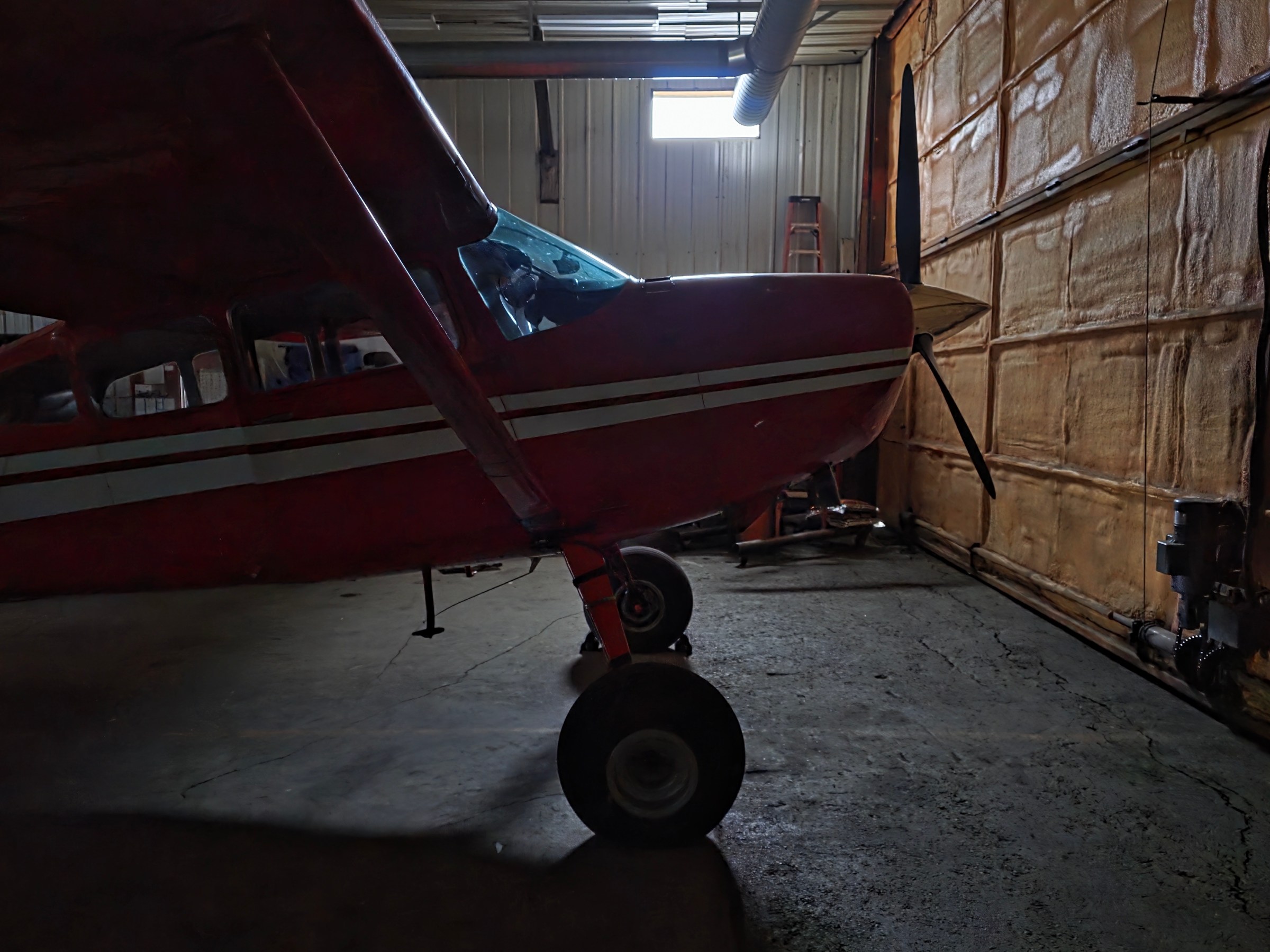 Red Cessna parked inside a dimly lit hangar.