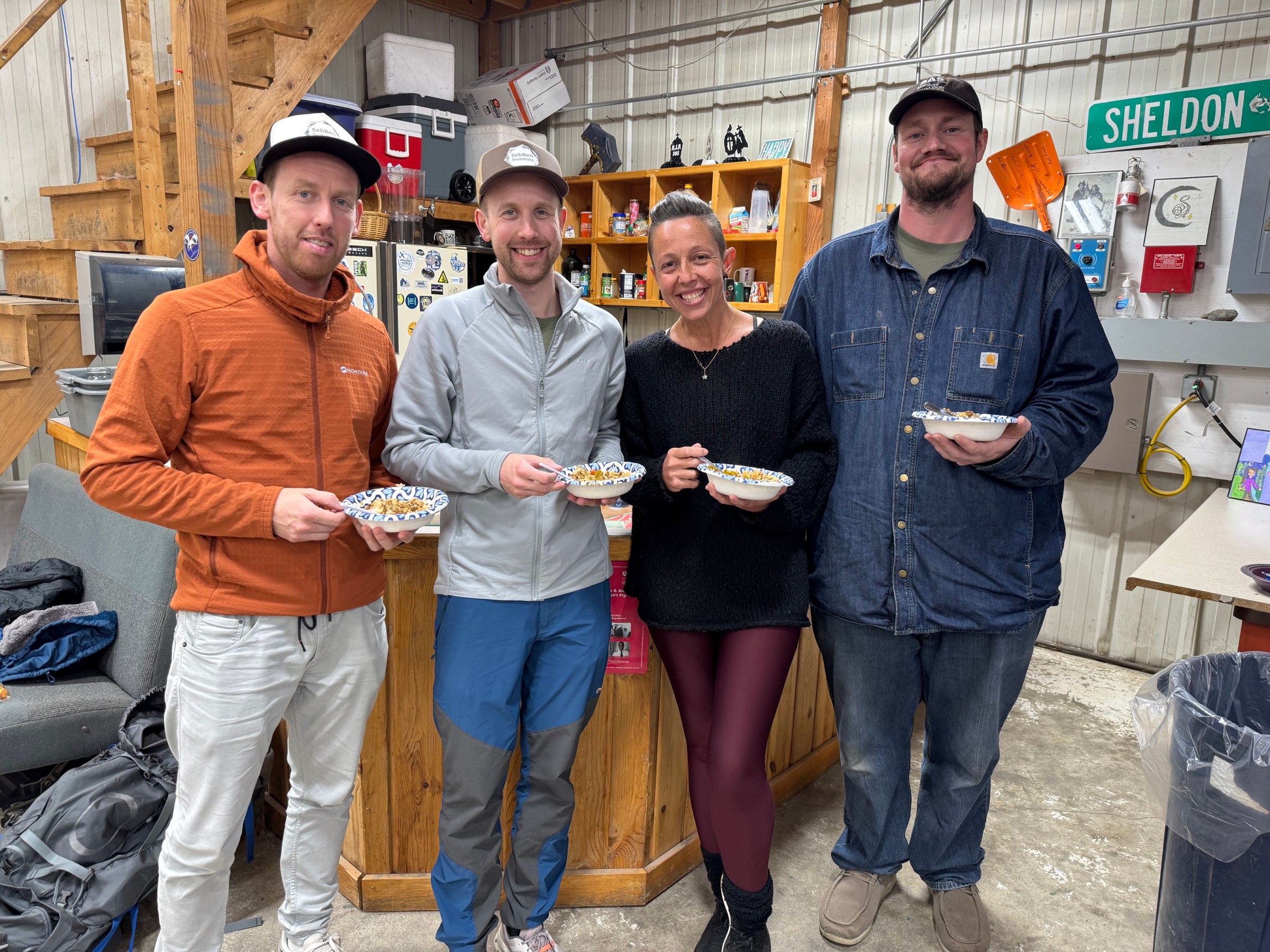 Four people in a workshop holding bowls, smiling at the camera.
