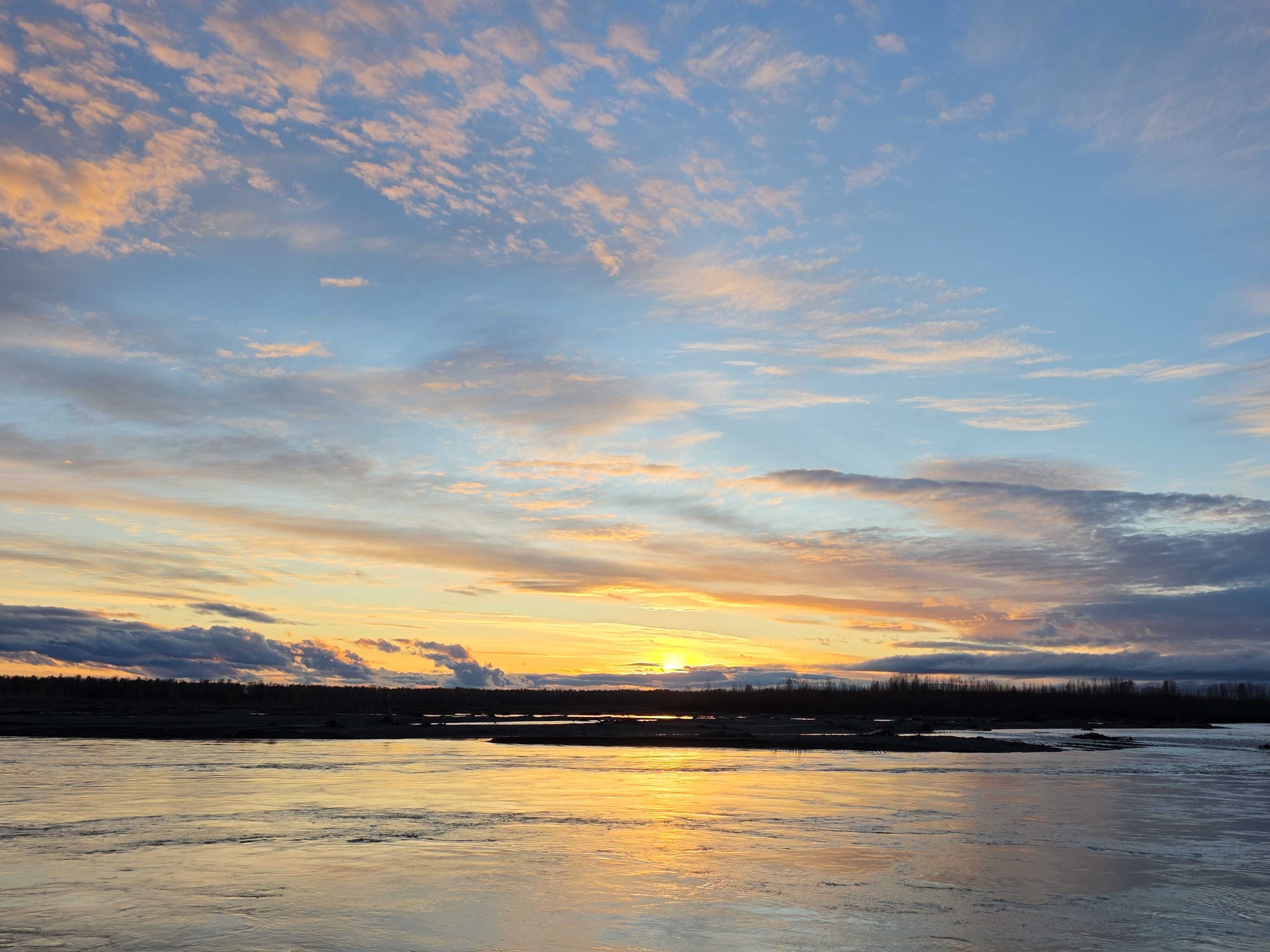 Sunset over a calm river with colorful clouds in the sky.