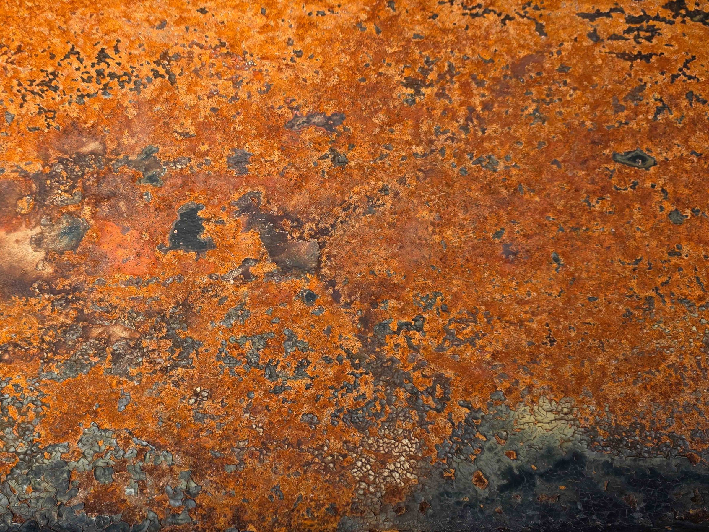 Close-up of textured rusty metal surface in shades of orange and brown.