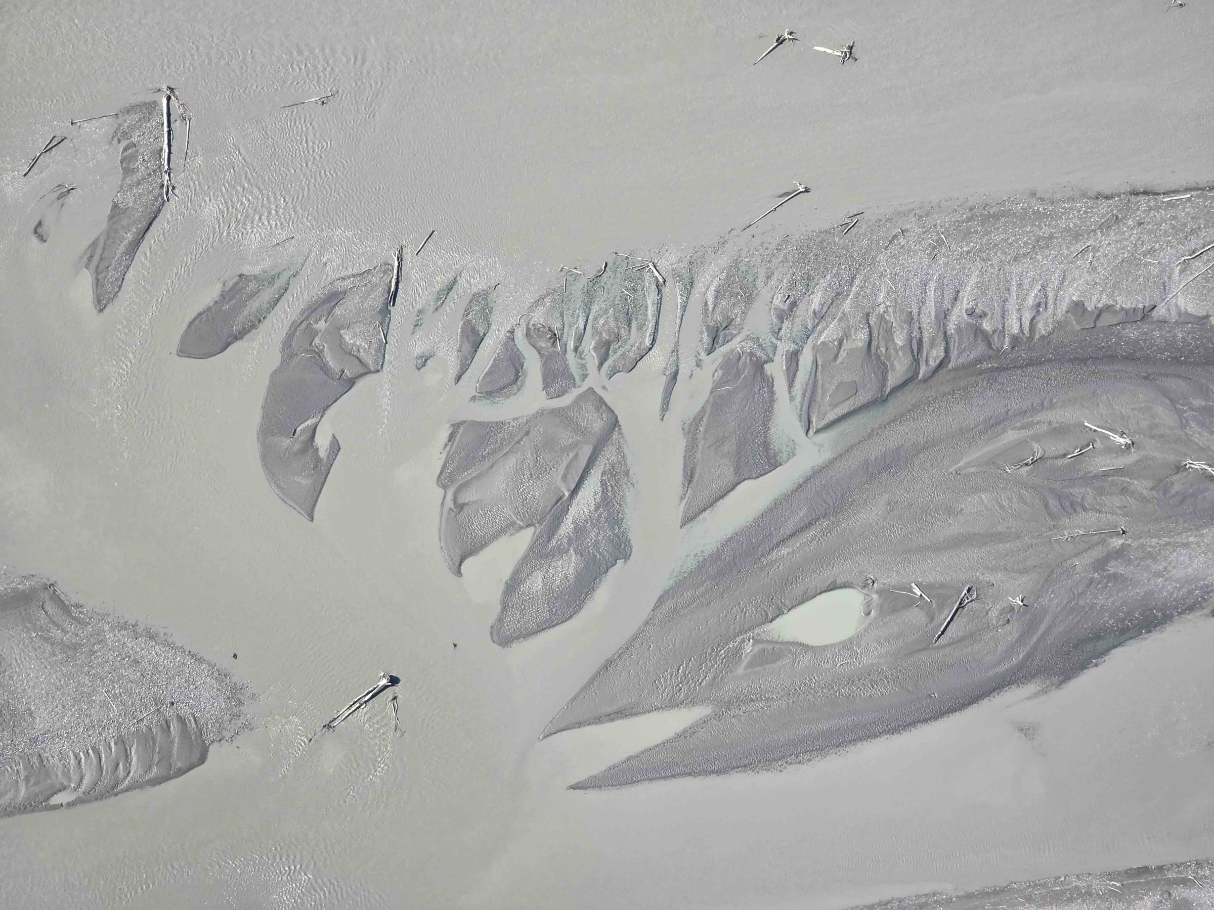 Aerial view of abstract river delta pattern in shades of gray and beige.