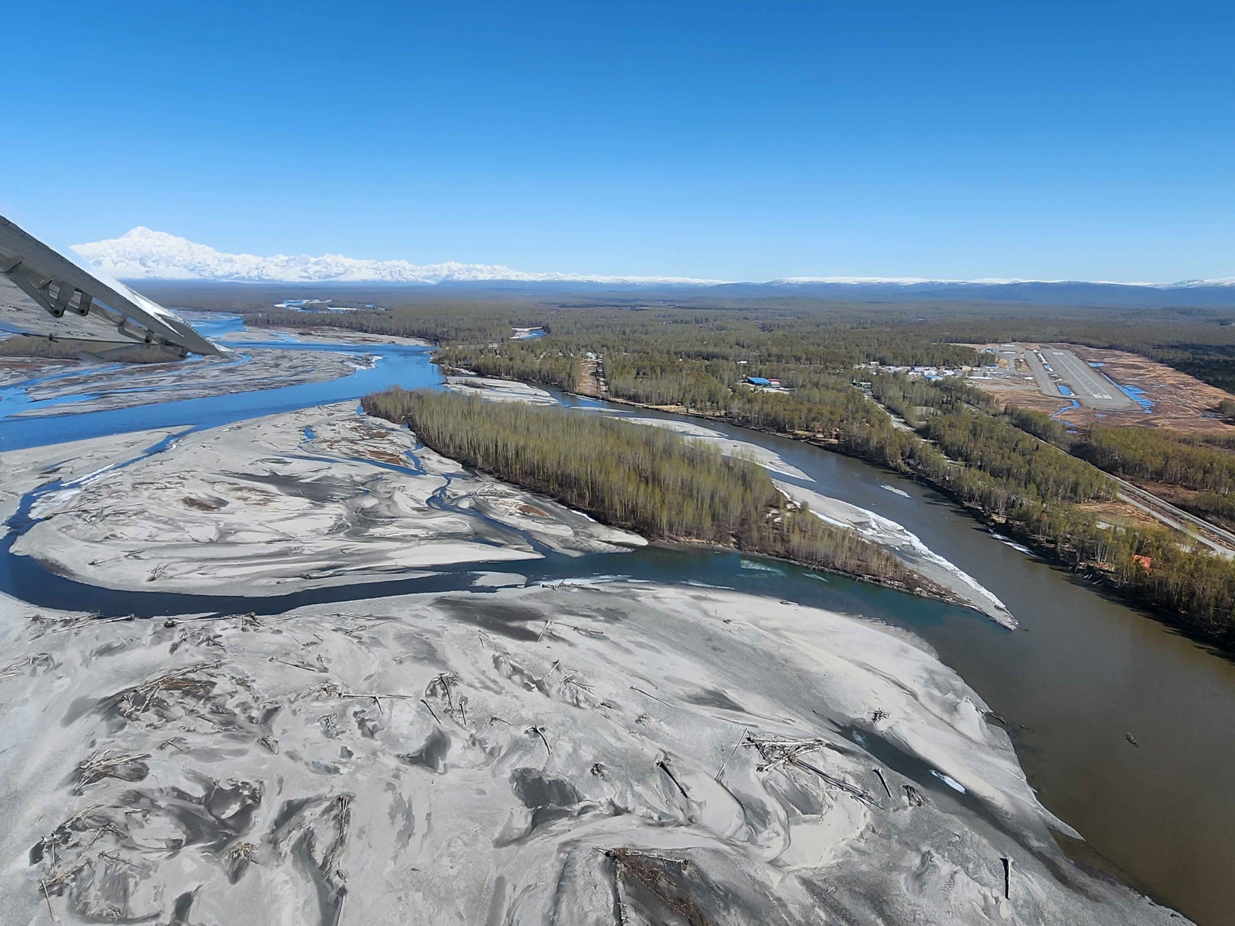 Aerial view of river delta and forest with airplane wing visible.