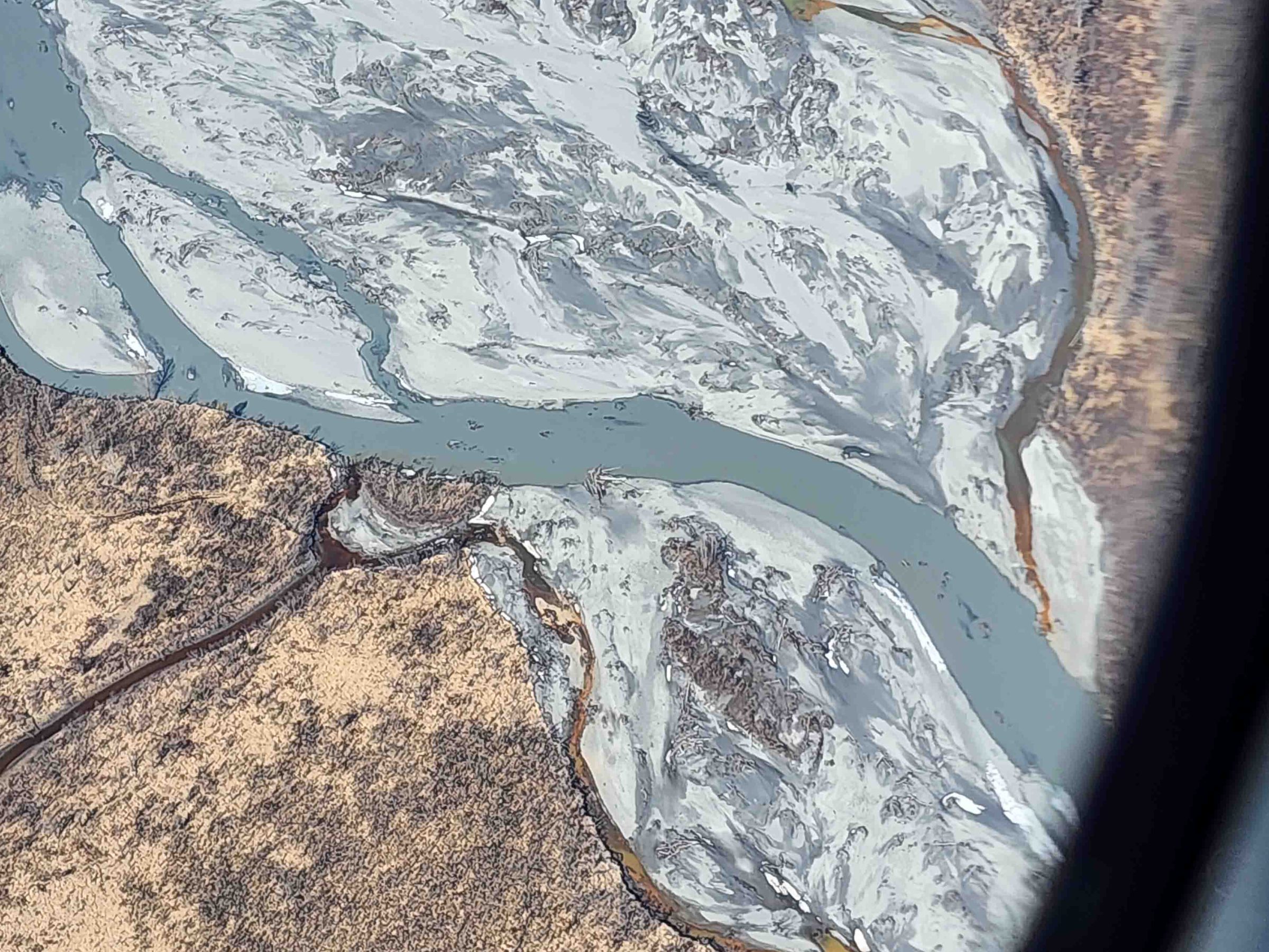 Aerial view of a winding river with muddy banks and surrounding dry landscape.