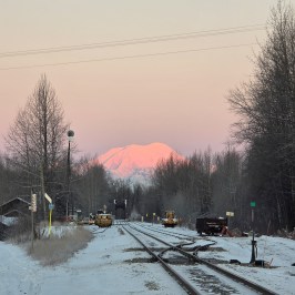 Snowy railroad tracks lead to Foraker under pink sky, winter Talkeetna Views