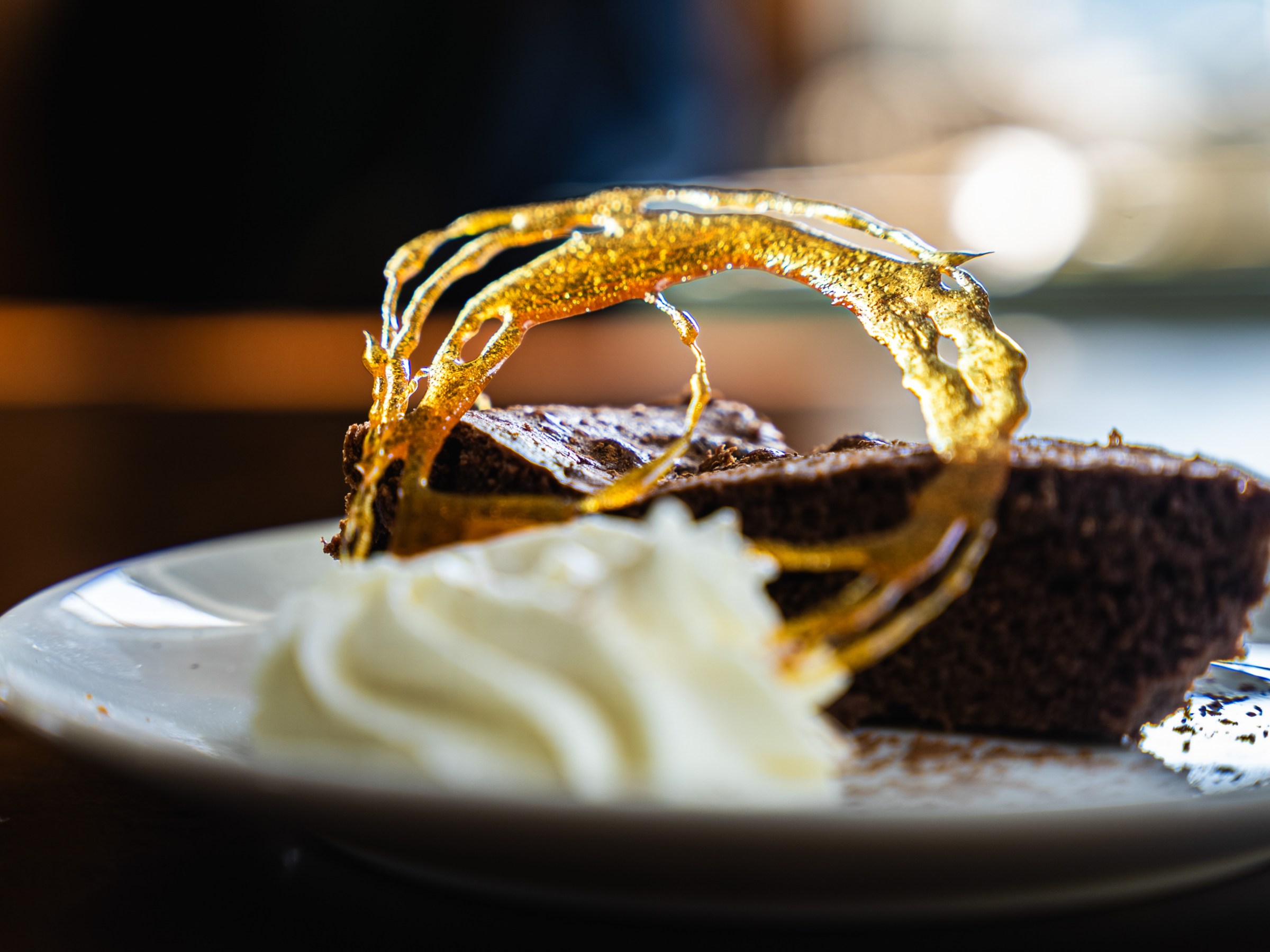 Chocolate cake with sugar decoration and whipped cream on a plate.