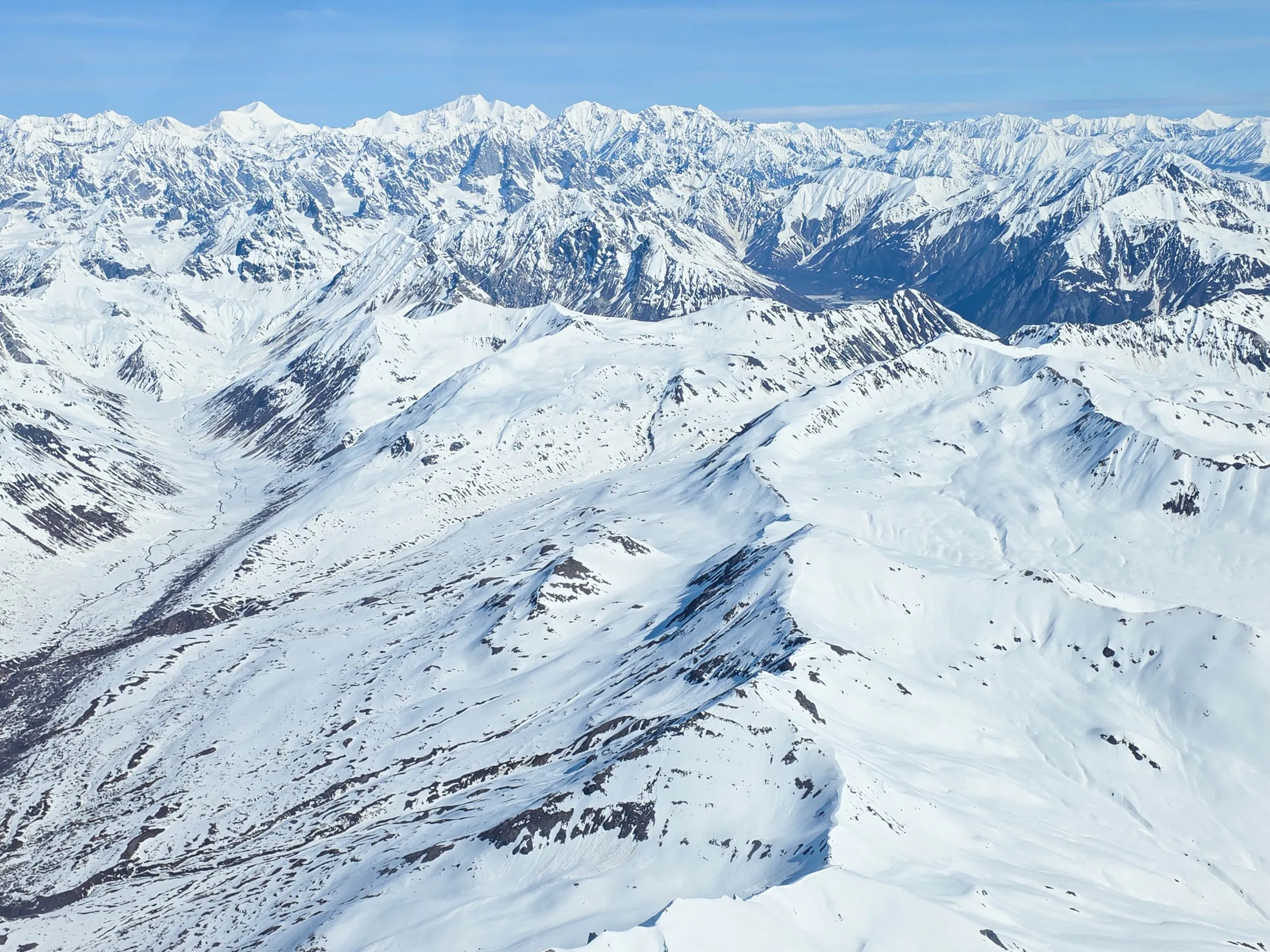 Snow-covered mountain range under a clear blue sky.