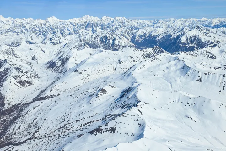 Snow-covered mountain range under a clear blue sky.