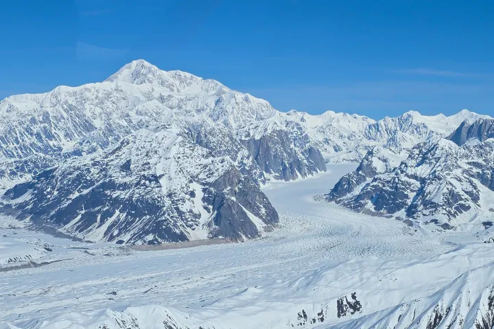 Snow-covered mountains and glacier under a clear blue sky.