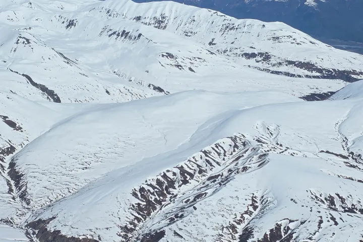 Snow-covered mountains and valleys under clear blue sky.