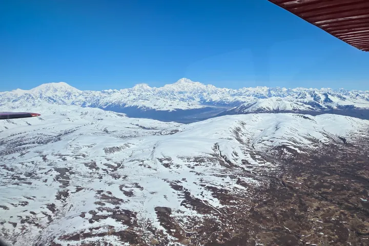 Aerial view of snow-covered mountains under a clear blue sky.