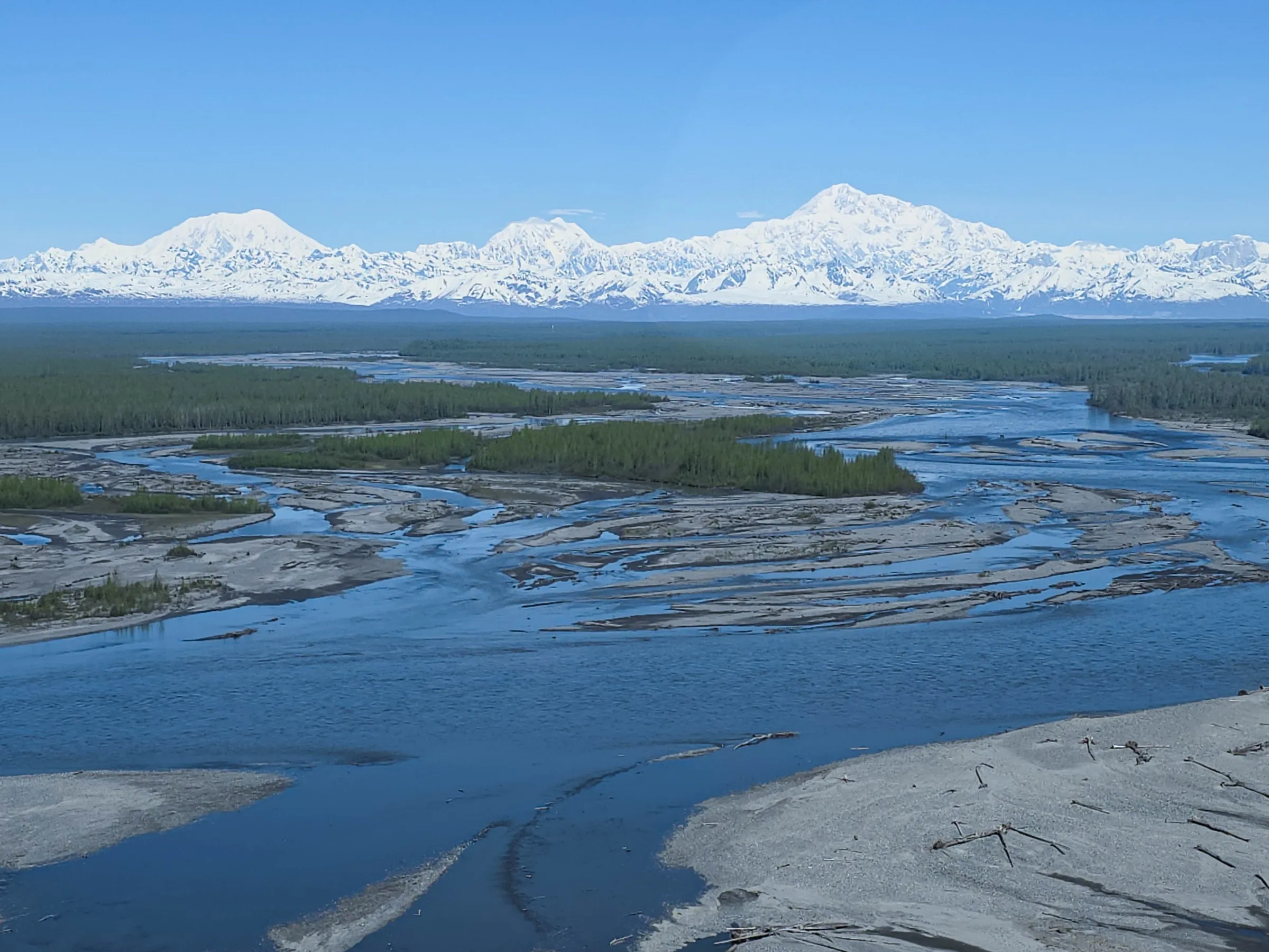 Aerial view of a river with snow-capped mountains in the background.