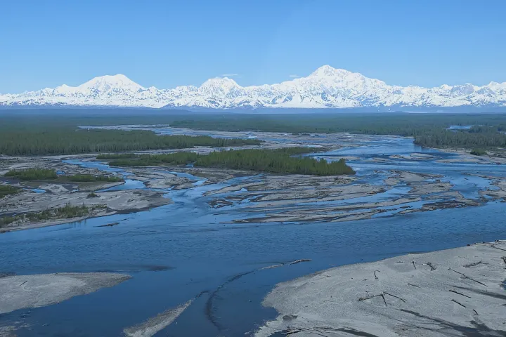 Aerial view of a river with snow-capped mountains in the background.