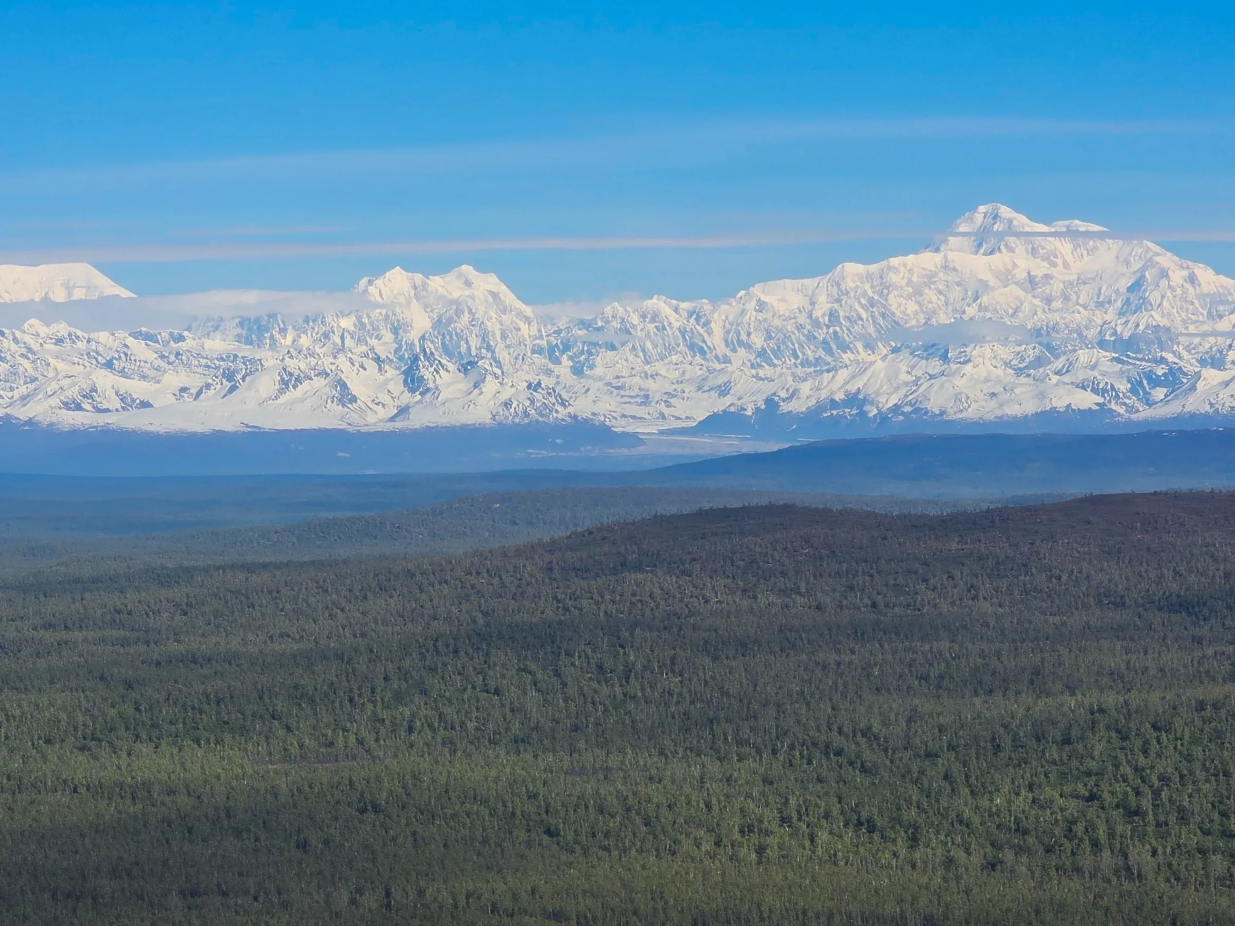 Expansive view of snow-capped mountain range under a clear blue sky.