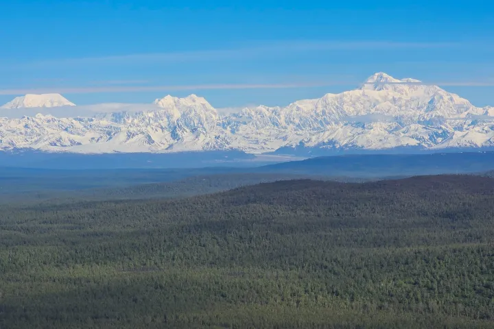 Expansive view of snow-capped mountain range under a clear blue sky.