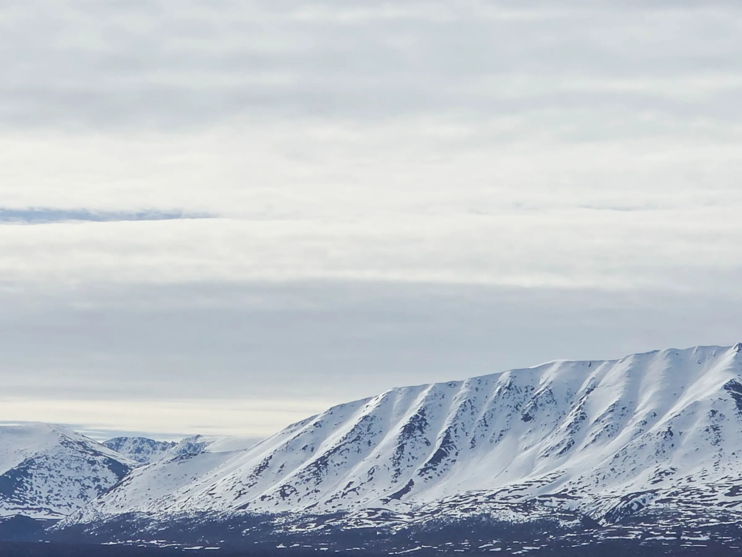 Snow-covered mountains under a cloudy sky.