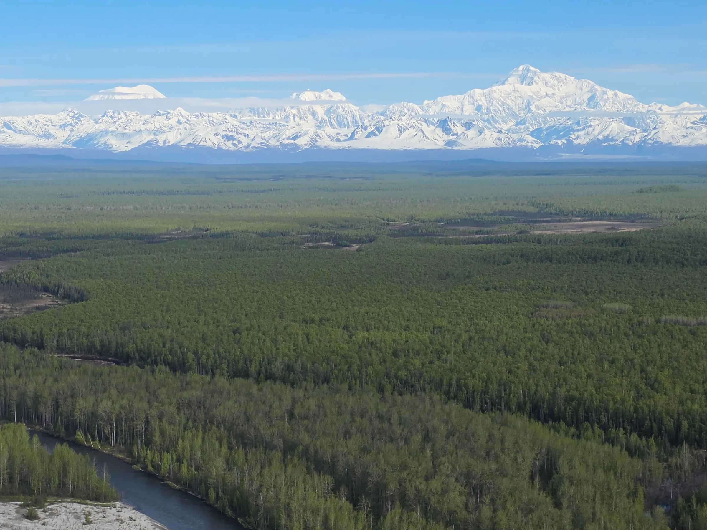 Snow-capped mountains under a blue sky with scattered clouds.