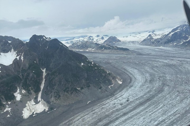 Aerial view of a winding glacier between rocky mountains.