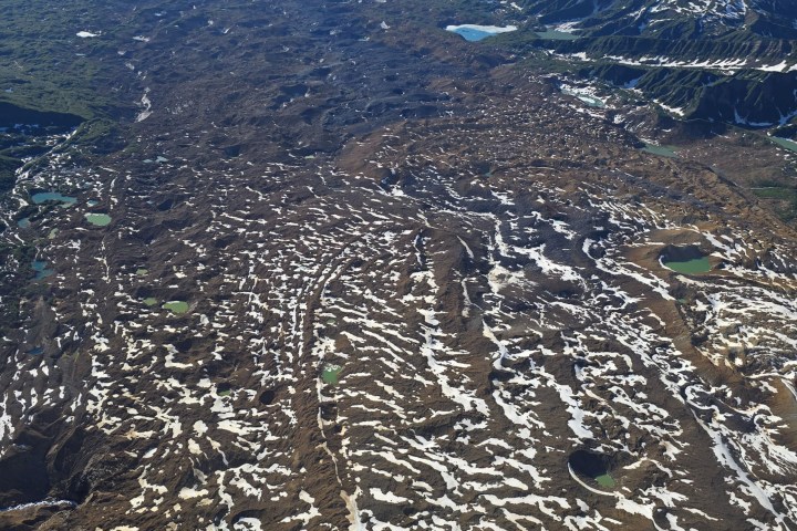 Aerial view of snow-covered mountains and valleys with small lakes.