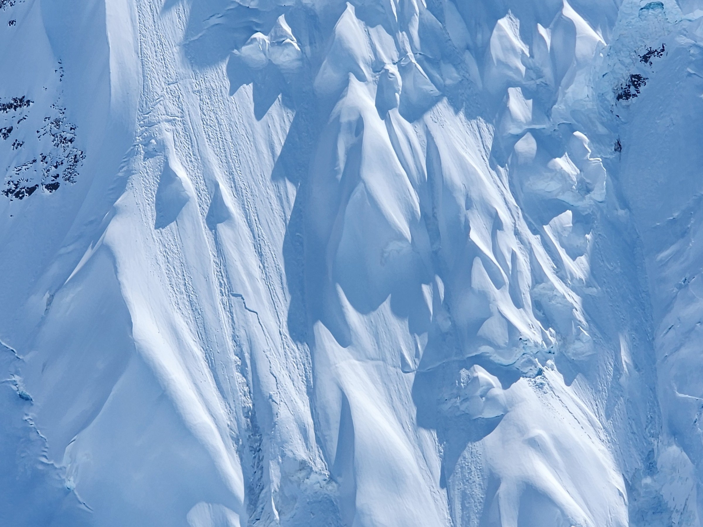 Snow-covered mountain slopes with jagged patterns.